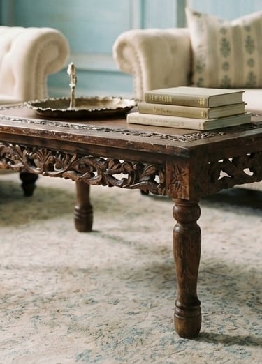 Hand-carved dark wood coffee table with books in a luxury living room setting.