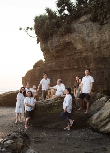 Multi generation family sitting together on coastal rocks at Nyanyi Beach Tabanan Bali during a lifestyle family photography 