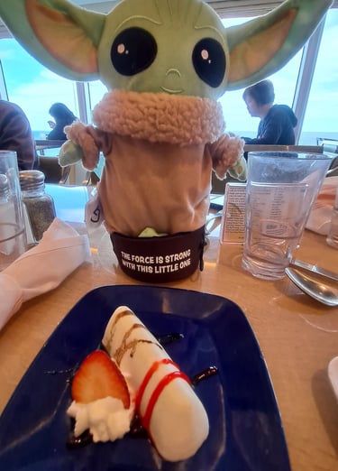 Little green companion on table in front of plate with Strawberry blintz