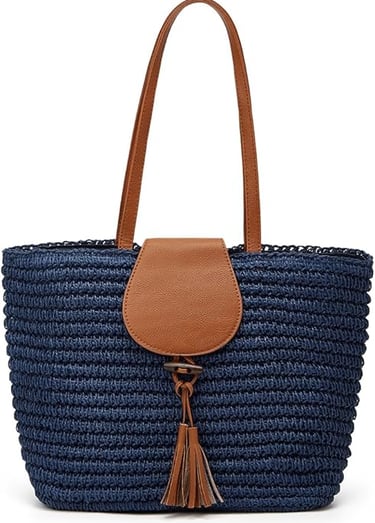 Navy blue woven straw tote bag with brown faux leather handles and a tassel accent for summer fashion.