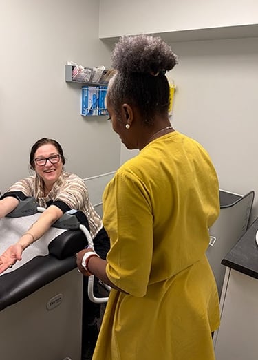 A patient in a doctors office using the BLT  Emsculpt on her arms talking to dr. aluko