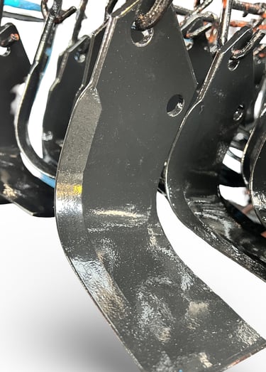 Durable black steel rotary tiller blades and cultivator tines for agricultural soil preparation.