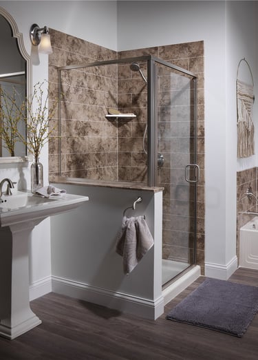 Modern bathroom with corner glass shower, stone tile walls, and pedestal sink
