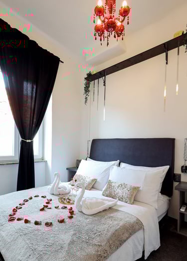 The photo shows honeymoon special setting of the bedroom in the BDSM Love Apartment. Champagne, rose petals, restraints.