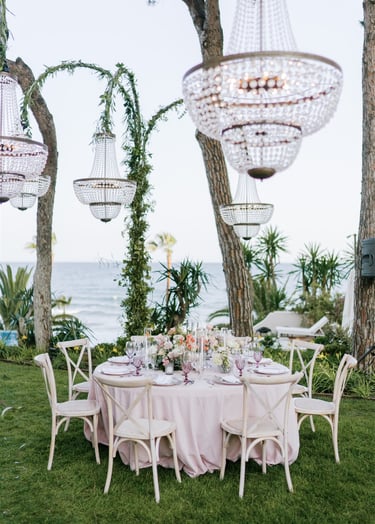 Elegant wedding table with pink linens, crystal chandeliers, and sea views at Villa El Rinconandles at Villa El Rincon