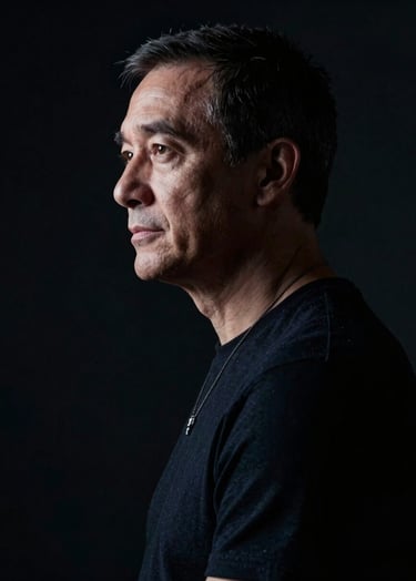 A cinematic portrait of a director in a dark studio setting. The lighting is low-key with off-white highlights on the profile, surrounded by deep black shadows. Professional and focused mood.
