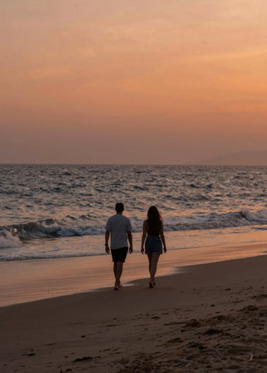 A cinematic wide-angle photograph of a couple walking along a soft sand beach at sunset. The sky is a warm terracotta orange and the waves have a soft charcoal blue tint. The lighting is sun-drenched and hazy, reflecting an authentic lifestyle photography style.