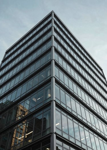 A vertical perspective shot of a contemporary glass and steel structure in Toronto. The image looks up towards a clear sky, emphasizing geometric patterns and negative space in a clean, professional style.