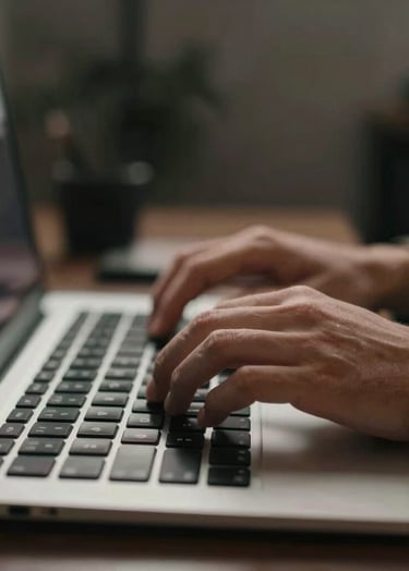 Close-up of human hands typing on a sleek keyboard in a low-lit, sophisticated room. The focus is on the movement, giving a spontaneous and cinematic feel. Palette includes #3A3F3B and #C1C4BF.