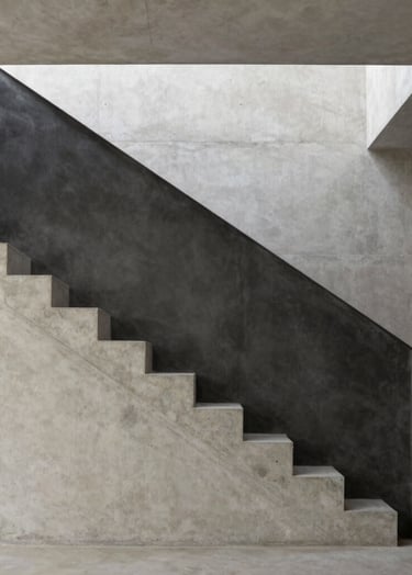 Architectural photography of a minimalist staircase with sharp geometric lines. The materials are raw concrete and Charcoal steel. Soft natural light creates dramatic shadows in a European Portuguese villa setting. Sophisticated and clean composition.
