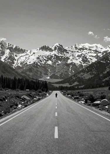 Wide-angle landscape shot of a straight road stretching toward snow-capped mountains in a Global / Western region, a single distant motorcycle rider as a small silhouette, high contrast black and white style.