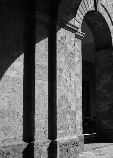 Black and white photography, architectural detail of the Laboratorio Arte Alameda in Mexico City, focusing on the interplay of light and shadow on stone walls, cinematic and contemplative style.