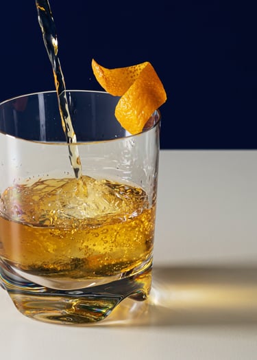 Product photography - drink being poured into a glass with an orange peel