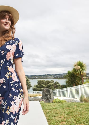 Fashion campaign photography - a woman in a dress and hat standing in front of a pool