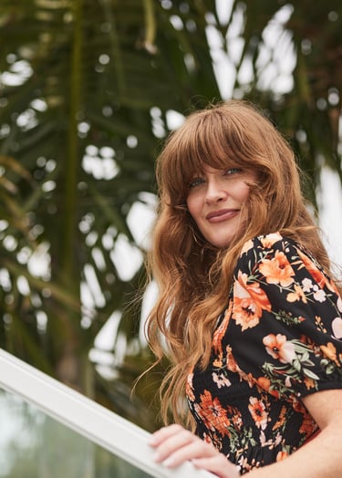 Fashion campaign photography - a woman in a floral dress standing on a balcony railing