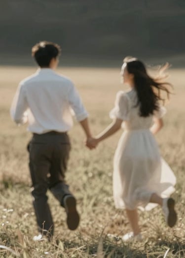 A blurry, artistic lifestyle shot capturing the couple running through a sun-drenched field. The motion blur adds a cinematic feel. Warm color palette with soft charcoal #3A3A3A shadows and bright #FDF8F0 highlights.