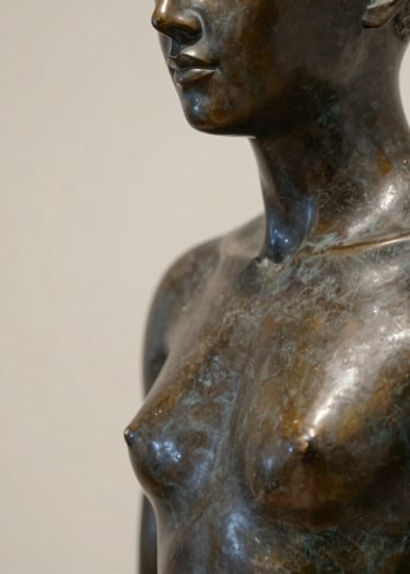 Close-up of a contemporary bronze sculpture, its surface catching soft, museum-quality light. The background is a minimalist wall in #CFC8B7 beige, highlighting the sophisticated dark bronze texture which reflects #1A1A1A tones.