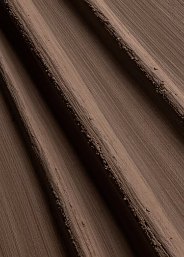 Macro photography showing the thick, tactile ridges of a painting created with muted earthy brown pigments. The lighting is low and directional, emphasizing the physical presence of the material. Artistic mood in a South American / Argentine studio.