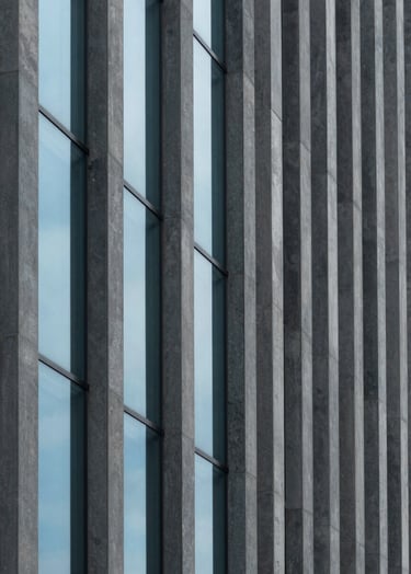 A minimalist architectural detail of a modern South American building facade. Clean vertical lines in dark grey concrete contrasted with soft baby blue glass windows. Professional photography, natural overcast light, focus on geometric shadows and textures.