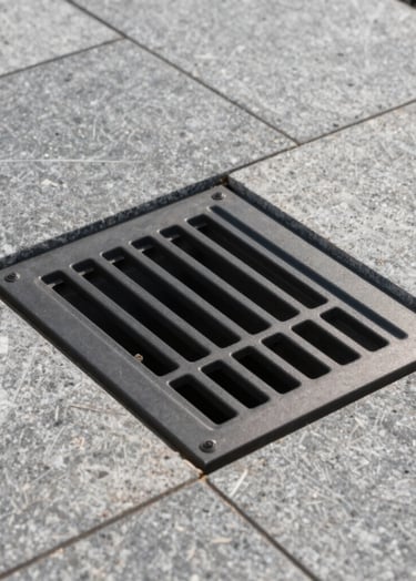 A professional architectural detail of a finished infiltration well cover, perfectly integrated into a modern stone pavement. Professional photography, minimalist style, emphasizing clean lines and quality construction.