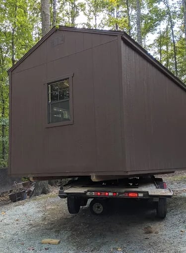 Shed being positioned for delivery with truck and trailer
