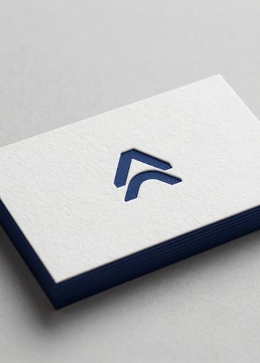 A close-up shot of a minimalist business card on thick 600gsm white cotton paper. The card features a debossed logo and edges painted in dark navy #0A1118. Sophisticated soft side-lighting to emphasize the deep texture of the letterpress. Professional and clean composition.