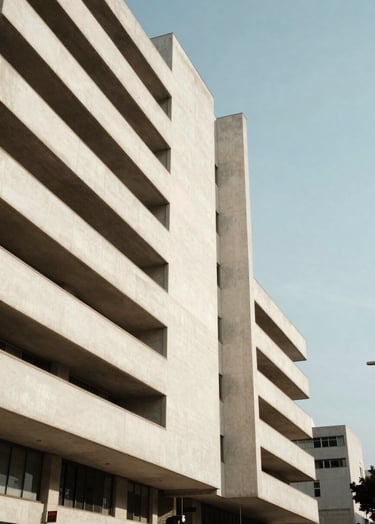 A cinematic vertical shot of a modern architectural building with minimalist lines in a Latin American / Hispanic capital city, bright midday sun creating sharp shadows, soft off-white concrete textures against a clear sky.