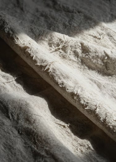 An oil study of light hitting a folded linen cloth. The composition uses deep charcoal shadows and soft off-white highlights to create a sense of depth and tangible texture.