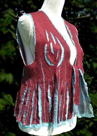 Handmade burgundy and turquoise nuno felted wool vest with fringe details on a mannequin outdoors.