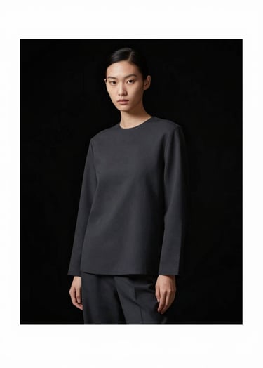 Full-frame portrait of a model in a sophisticated, minimalist pose. The model wears a dark charcoal garment (#363636) against a total black background (#000000). Lighting is refined and artistic, highlighting the silhouette with a touch of beige (#B5A591).
