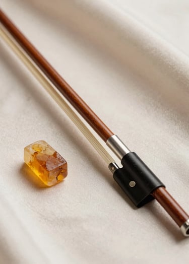 A detailed shot of a violin bow and a block of amber rosin on a soft off-white silk cloth. The scene is elegant and professional, reflecting the high-quality musical standards of a Southern European / Spanish artist. Palette colors: muted earthy brown and warm silver taupe.