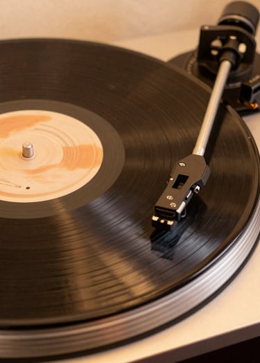 An artistic shot of a vinyl record player spinning a disc. The lighting creates a warm glow in burnt sienna and soft cream, emphasizing the analog and organic nature of the music.