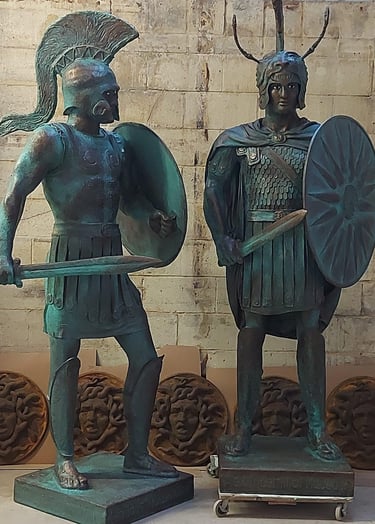 Statues of Alexander the Great and Leonidas with shields and swords.