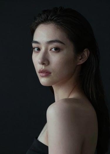A cinematic portrait of a woman with soft off-white highlights on her face, emerging from a deep charcoal black background. Her expression is calm and thoughtful. Minimalist composition with a focus on lighting and texture.