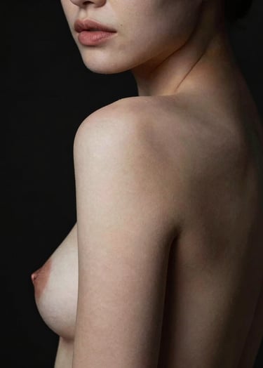 Artistic nude portrait focusing on the curvature of the shoulder. High contrast soft white highlights and midnight black background. Minimalist style.