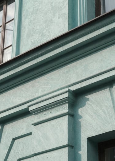 A close-up photograph of a vintage architectural detail with clean lines, shot in natural daylight. The palette features Muted Teal and Soft Sage tones against a Pale Frost building surface, showing texture and historical depth with professional focus.