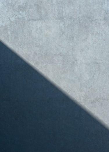 Abstract photography of light and shadow on a matte concrete surface, muted blue tones, clean composition, architectural and refined style, Global / Contemporary Art.