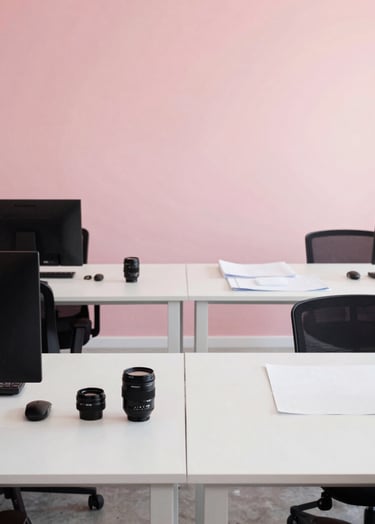 A minimalist office setting for a construction studio in Latin America. Architects working with modern tools, clean white desks, black details, and a soft pink wall in the background. Professional and reliable atmosphere.