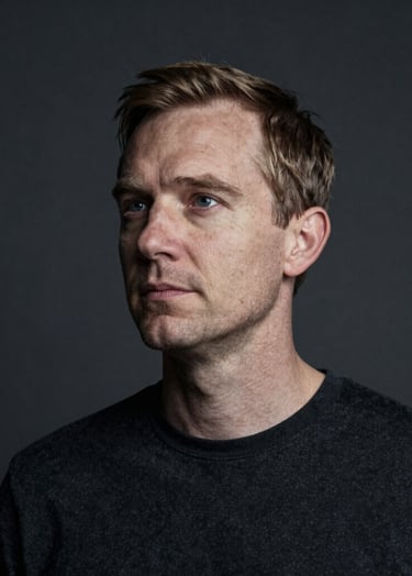 An atmospheric, storytelling portrait of a Northern European / Dutch subject in a minimalist studio. The composition uses generous whitespace and a dark aesthetic. Soft off-white light catches the side of the face against a charcoal background.