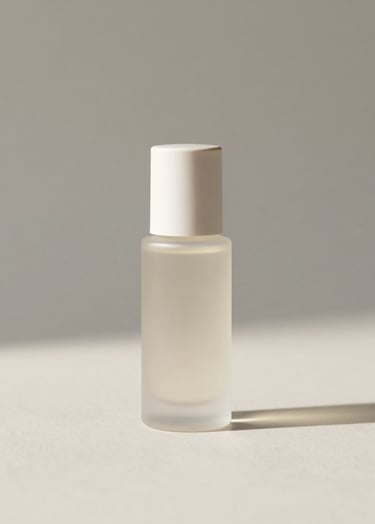 A high-end, minimalist studio setup. A single luxury skincare bottle in frosted glass sits centered on a matte cream surface (#F8F5F2). The lighting is soft and diffused from the side, creating long, subtle shadows. The background is a clean, neutral gray (#D8D8D8). The aesthetic is sophisticated and precise, with significant negative space around the product.
