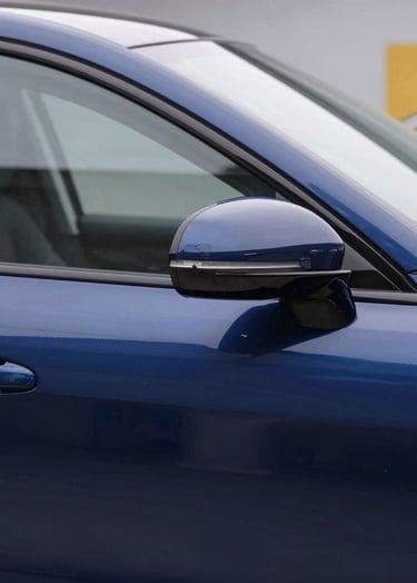 Detailed 'After' shot of a luxury car door, perfectly smooth with zero dents, reflecting a clean workshop environment. Professional lighting highlighting the deep blue paint. Style: High-end automotive photography with brand colors #0A1E3C and #E7C670 subtly present in the workshop background.