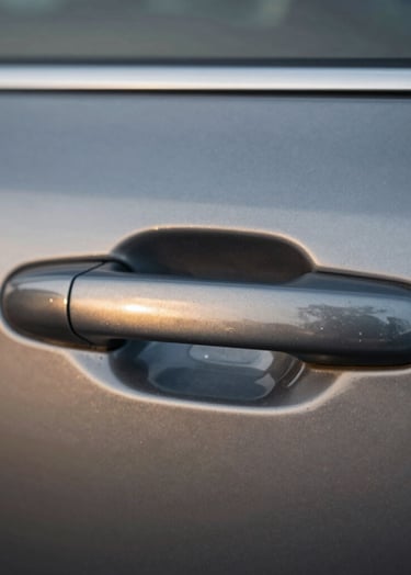 Extreme close-up of a car door handle area, completely smooth and free of dents, reflecting a sharp and clear gold horizon line, emphasizing the quality of the finish and the original paint preservation.