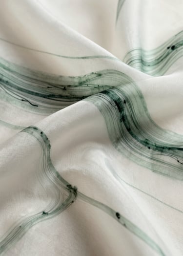 A minimalist, abstract ink drawing on translucent off-white silk. Fine, organic lines in dark slate green and muted sage green weave through the fabric, creating layers of depth. The lighting is soft and ethereal, highlighting the texture of the silk threads.