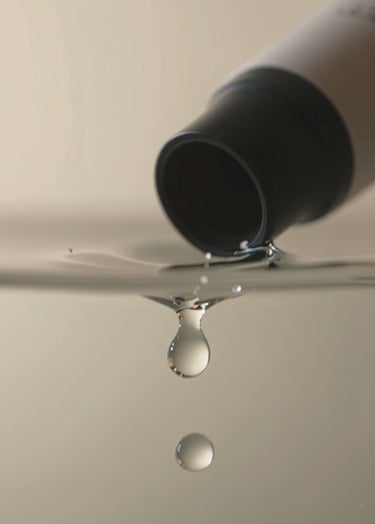 Macro shot of a product being submerged in water with high-speed lighting capturing every droplet. The style is sharp and commercial, with a clean background in sand tones (#F8F4ED) and charcoal (#363131) depth.