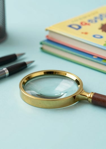 A sophisticated workspace scene with a mix of academic ink pens, a magnifying glass, and a stack of colorful children's storybooks. The palette includes #7A9E9F teal and #D4B281 gold accents, suggesting a resourceful and imaginative professional environment.