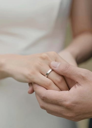 A close-up of two hands intertwined, showing wedding bands, with a soft #B8ADAD blurred background, warm and trustworthy atmosphere, timeless photography style.