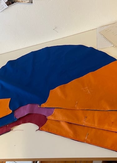 A colorful fabric pattern for a cape pinned and laid out on a white sewing table.