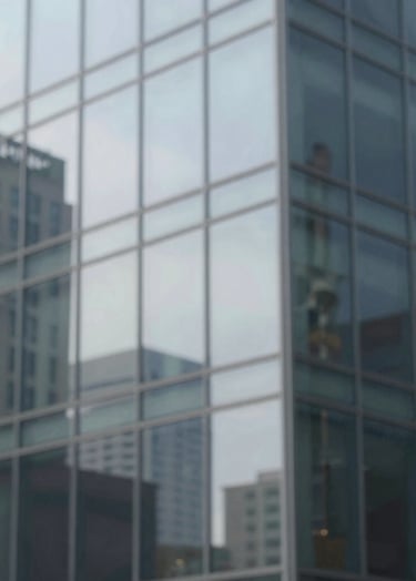 Abstract view of a glass building reflecting the surrounding urban environment. The reflection is slightly distorted, creating a painterly effect. Minimalist and elegant composition using #F5F7FA and #2F363F.