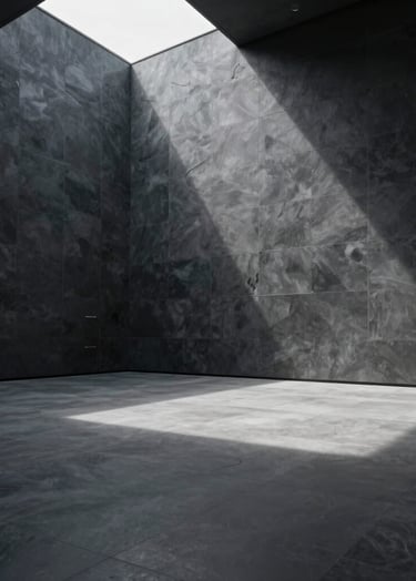 Wide-angle architectural photography of a minimalist interior space with dark slate gray walls. A single soft silver light source from above creates long shadows, simulating the interior of a futuristic outpost in a North American / US setting.
