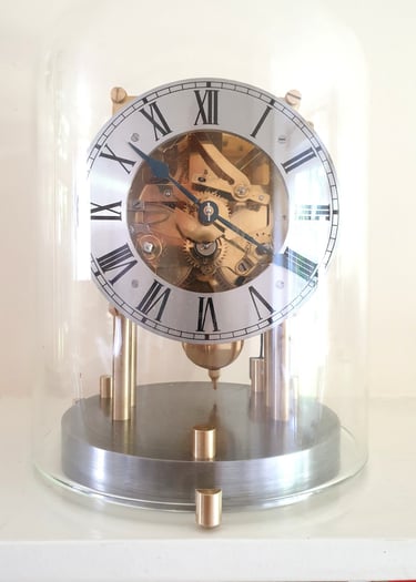 Mantel clock movement with roman numerals and glass dome.
